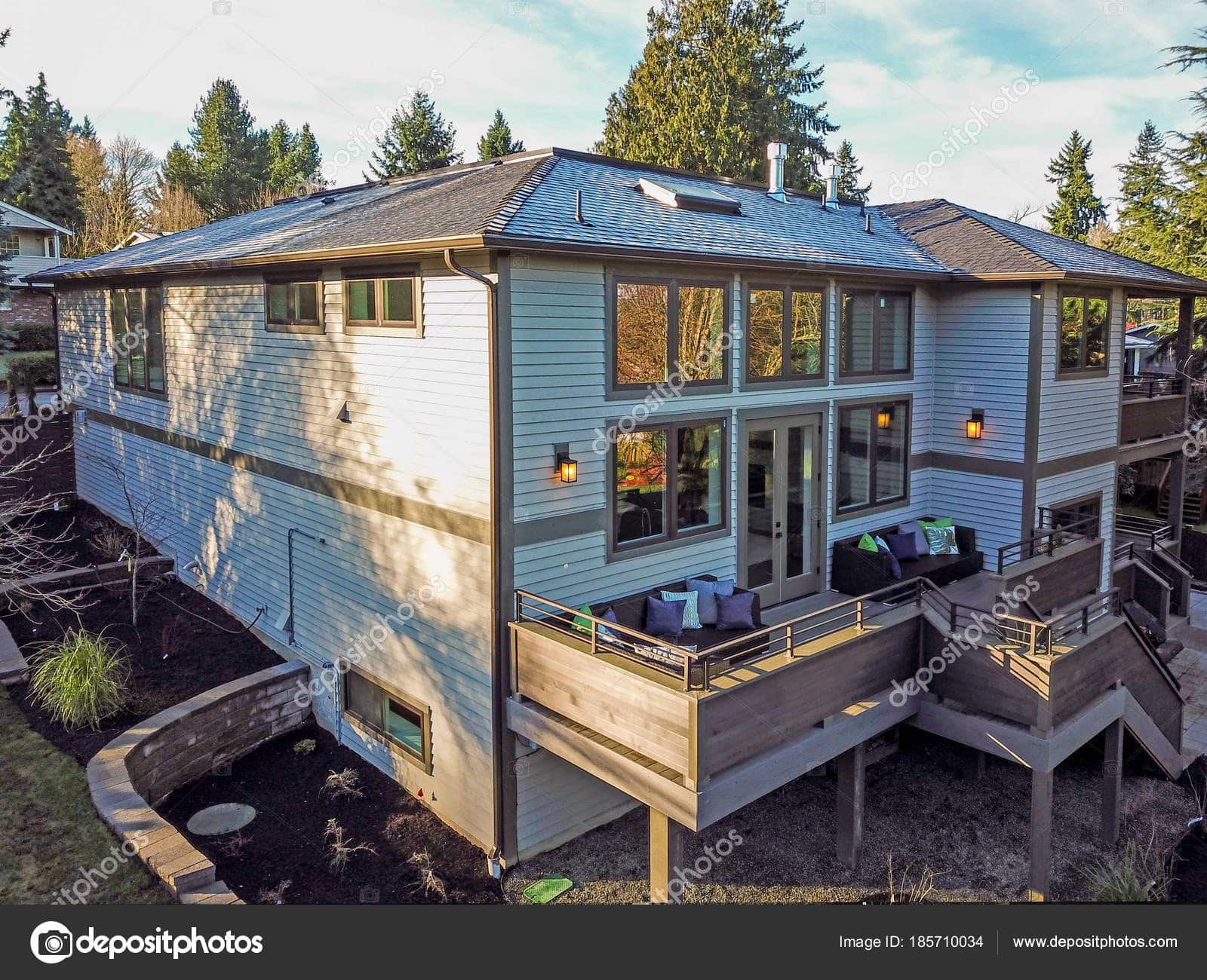New construction home exterior boasts luxury oversized deck overlooking a Well-designed garden.